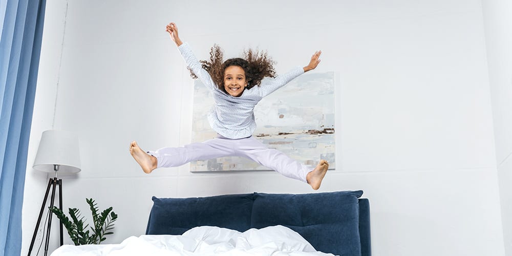 Young girl jumping on a bed